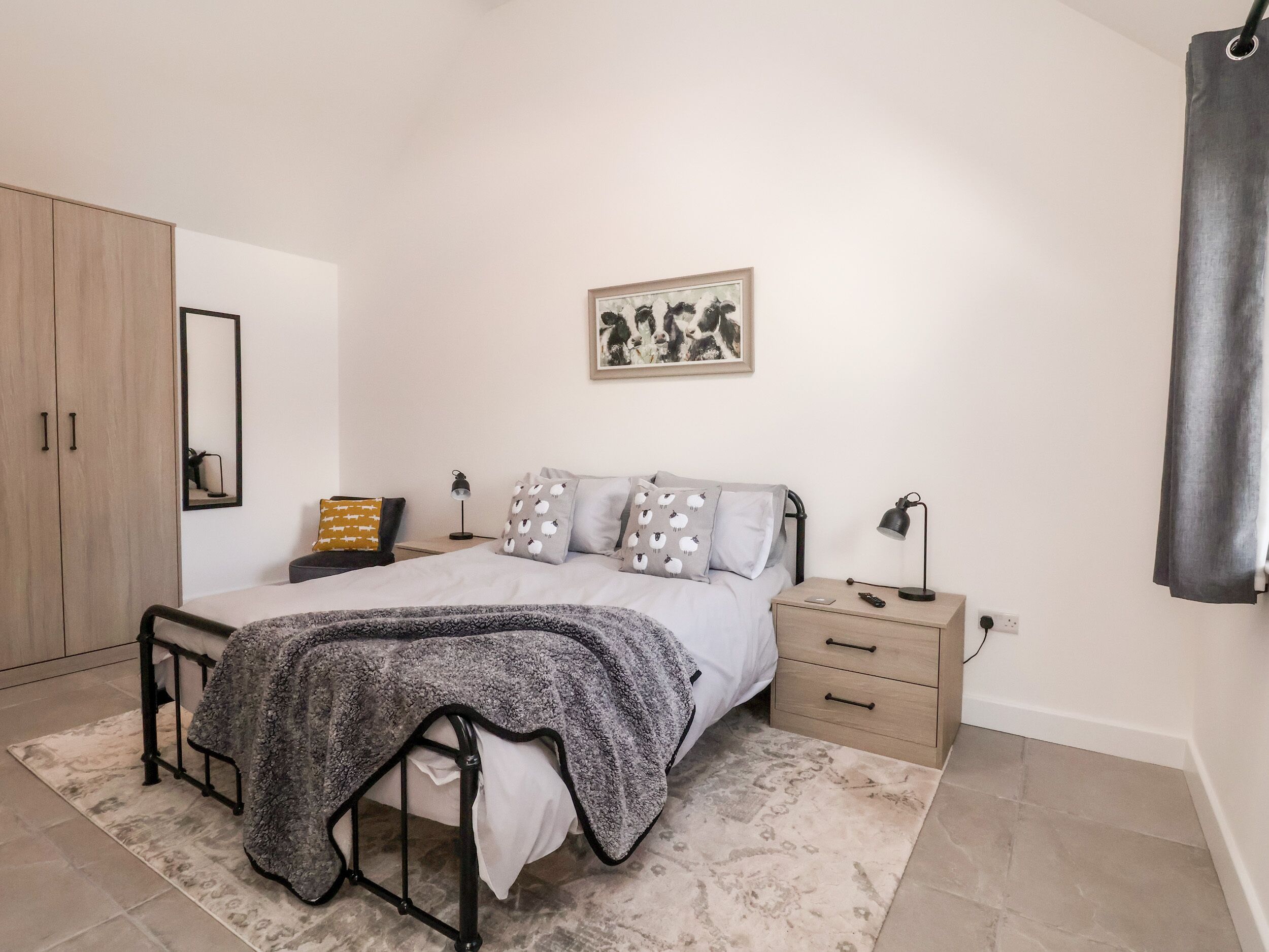 A bedroom with a bed, bedside tables, a wardrobe, and a mirror.