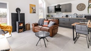 Una sala de estar moderna con chimenea, un sofá de cuero, una mesa de centro y un comedor con una silla de metal.