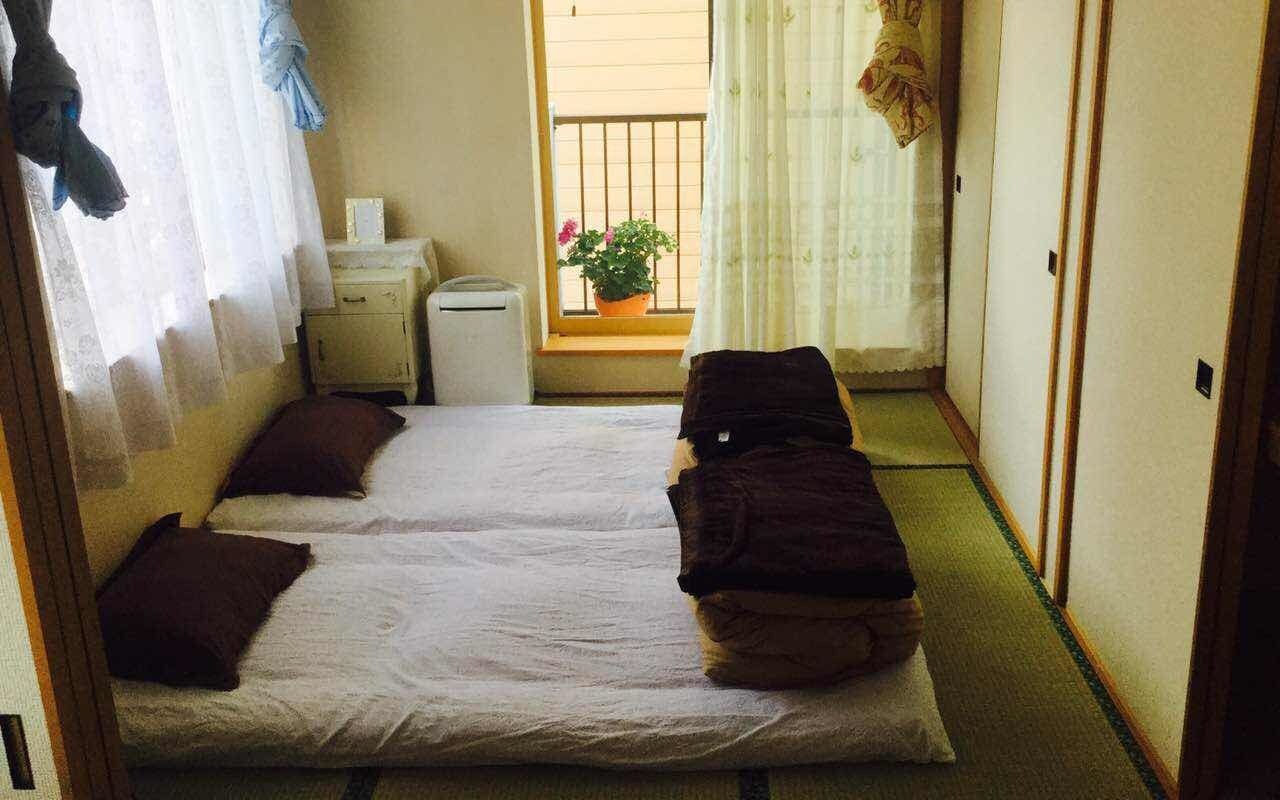 A narrow room with two beds and a small window.