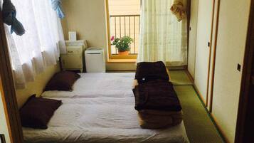 A narrow room with two beds and a small window.