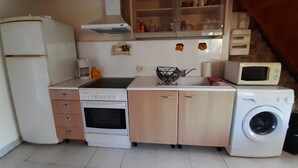 Ett kompakt kök med kylskåp, spis, mikrovågsugn och tvättmaskin.