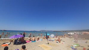 En fullsatt strand med folk som solar och badar.