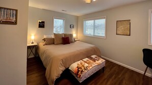 A bedroom with a bed, a nightstand, a ceiling fan, and a window with blinds.