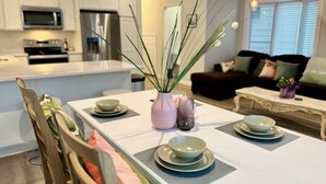 A modern kitchen with white cabinets, stainless steel appliances, and a dining area with a white table set for four.