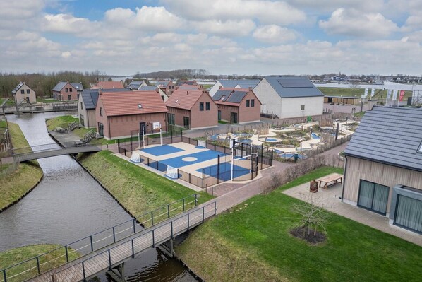 A residential area with houses, a canal, and a sports court.