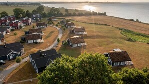 A coastal village with houses, a pathway, and a view of the sea. - Bungalow by the Sea with Sauna in Germany (Sierksdorf)