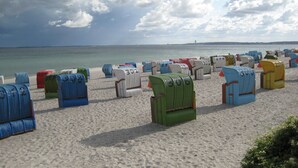 A beach with rows of colorful beach chairs and umbrellas. - Bungalow by the Sea with Sauna in Germany (Sierksdorf)
