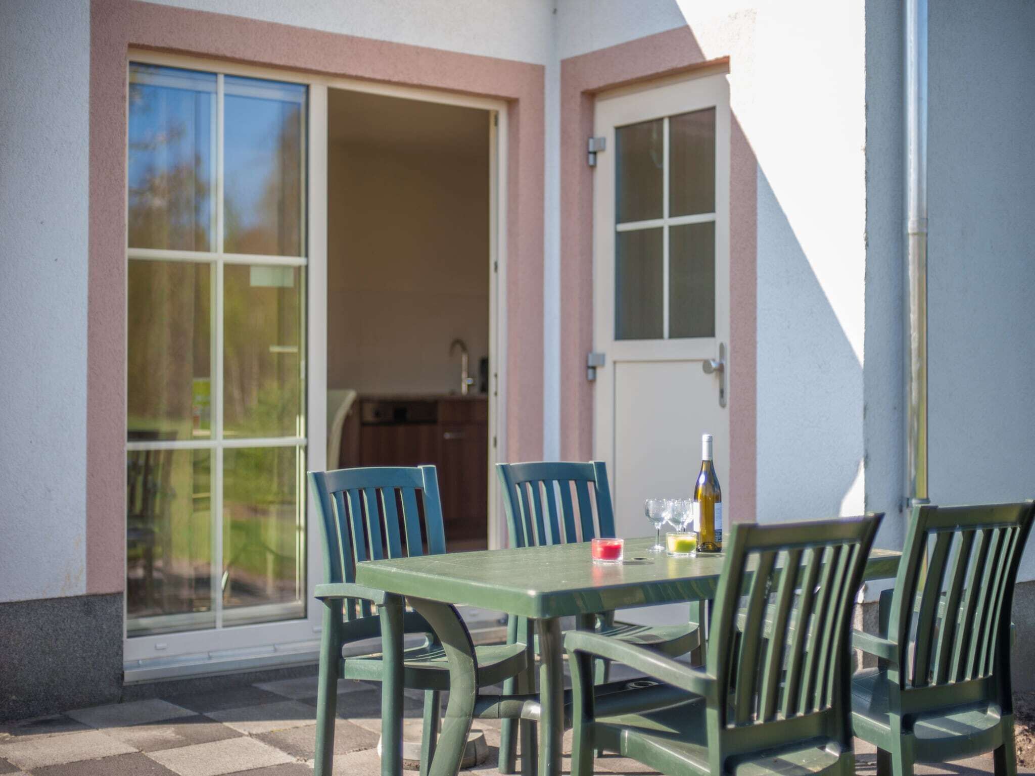 A patio with a table and chairs, a bottle, and a glass.