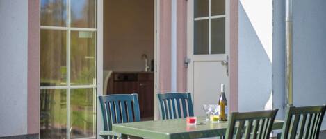 A patio with a table and chairs, a bottle, and a glass.