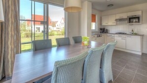 Eine moderne Küche mit weißen Schränken, einem eingebauten Ofen und einem großen Fenster.