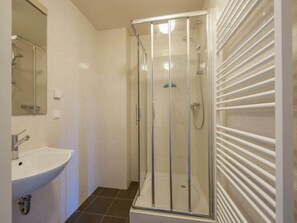 A modern bathroom with a glass-enclosed shower, a white sink, and a mirror. - Villa with Outdoor Space (Bad Bentheim)