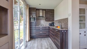 A modern kitchen with dark wood cabinets, a stainless steel oven, and a granite countertop. - Villa with bubble bath, solarium and fireplace (Dahlem)