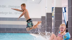 Ein Kind springt in einen Pool, Wasser spritzt herum.