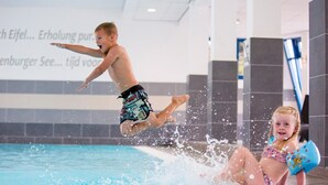 Un enfant saute dans une piscine, l’eau éclabousse tout autour.