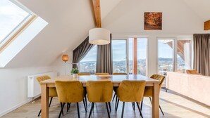 A dining area with a table, chairs, a pendant light, and a city view through large windows. - Spacious, modern apartment, near center (Winterberg)