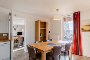 Ein moderner Essbereich mit Holztisch, Stühlen und einer Pendelleuchte.