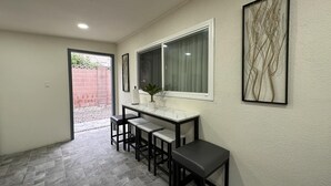 Eine kleine Küche mit Marmorarbeitsplatte, einem Fenster mit Vorhängen und einem Blumentopf.