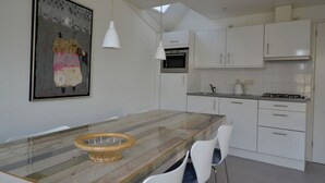 Een moderne keuken met witte kastjes, een houten eettafel en hanglampen.