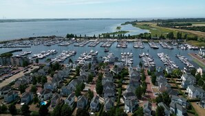 A marina with numerous boats docked, surrounded by residential houses. - Apartment in Cape Helius by the Waterside (Hellevoetsluis)
