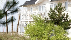 A two-story building with a balcony, surrounded by trees and grass. - Apartment in Cape Helius by the Waterside (Hellevoetsluis)