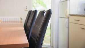 A dining area with a wooden table and black upholstered chairs.