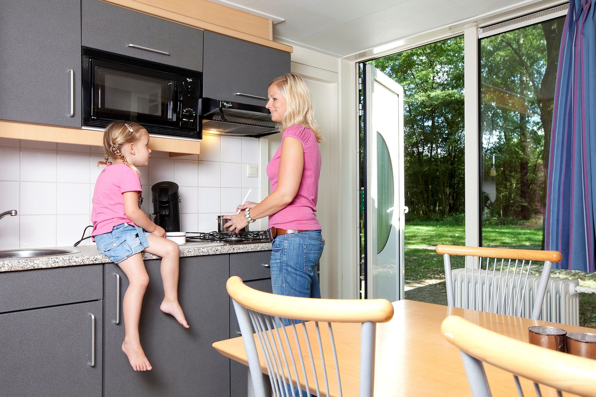 A modern kitchen with a built-in microwave, a coffee machine, and a dining area with a table and chairs.