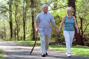 Two people walking on a paved path in a wooded area.