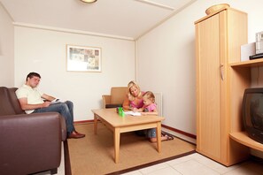 En stue med en brun lædersofa, et træ sofabord, et fjernsyn og et skab.