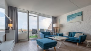 Un salon moderne avec un canapé bleu, une table basse et un tableau accroché au mur.
