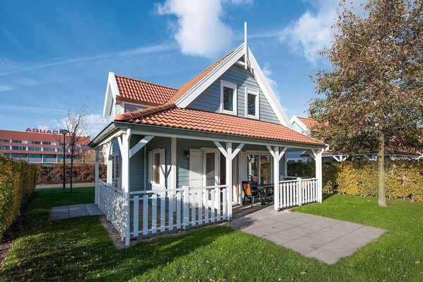A house with a red-tiled roof, a white porch, and a small garden.