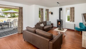 Un salon moderne avec un canapé, une petite table, un fauteuil turquoise et une cheminée.