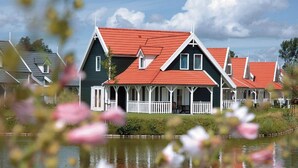 Tyynen järven rannalla sijaitsee rivi perinteisiä taloja, joissa on punaiset katot ja valkoiset kaiteet.