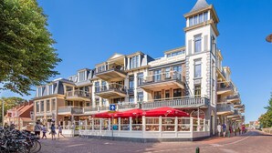 A multi-story hotel with balconies, outdoor seating, and a clear blue sky. - Modern Domburg Apartment (Domburg)