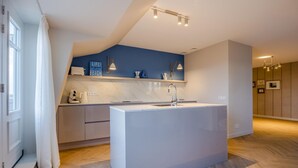 A modern kitchen with a central island, white cabinetry, and blue accent walls. - Apartment in Domburg near the Beach (Domburg)