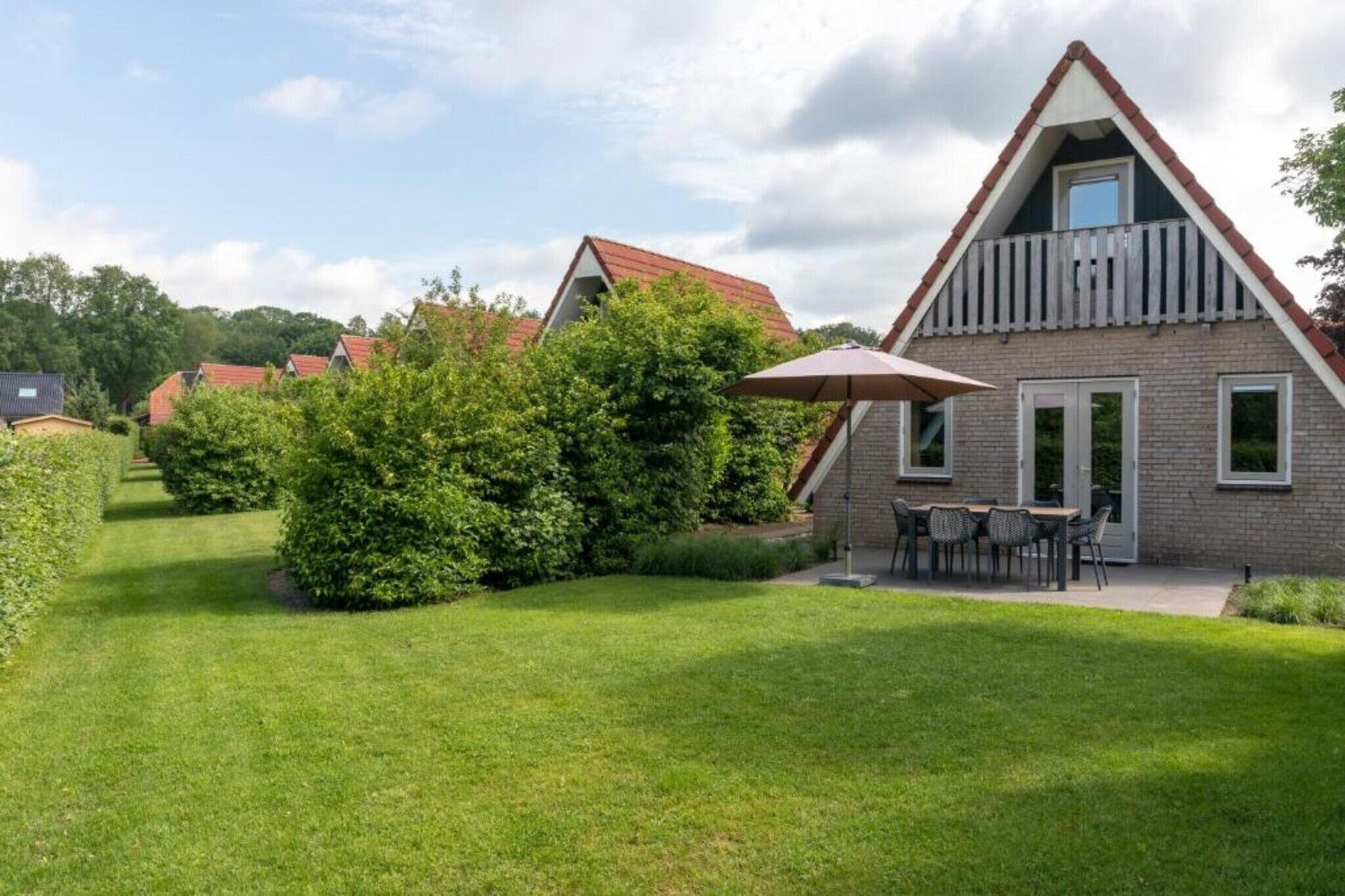 Ein modernes Haus mit einem Satteldach, einem Balkon und einem gepflegten Rasen.