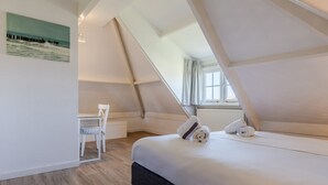Un dormitorio con cama, una silla y un cuadro en la pared.