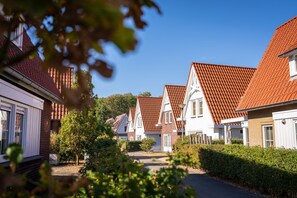 A row of traditional houses with red-tiled roofs, white walls, and a clear blue sky. - Chic Villa by the Sea (Koudekerke)