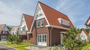 A residential house with a red-tiled roof, brick exterior, and a front porch.