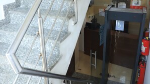 A staircase with metal railings leading to a reception area with a desk and a fire extinguisher. - Hotel Shilo inn  (New Delhi)