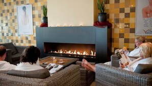 Ein Loungebereich mit Kamin, Sitzgelegenheiten und Zierpflanzen.
