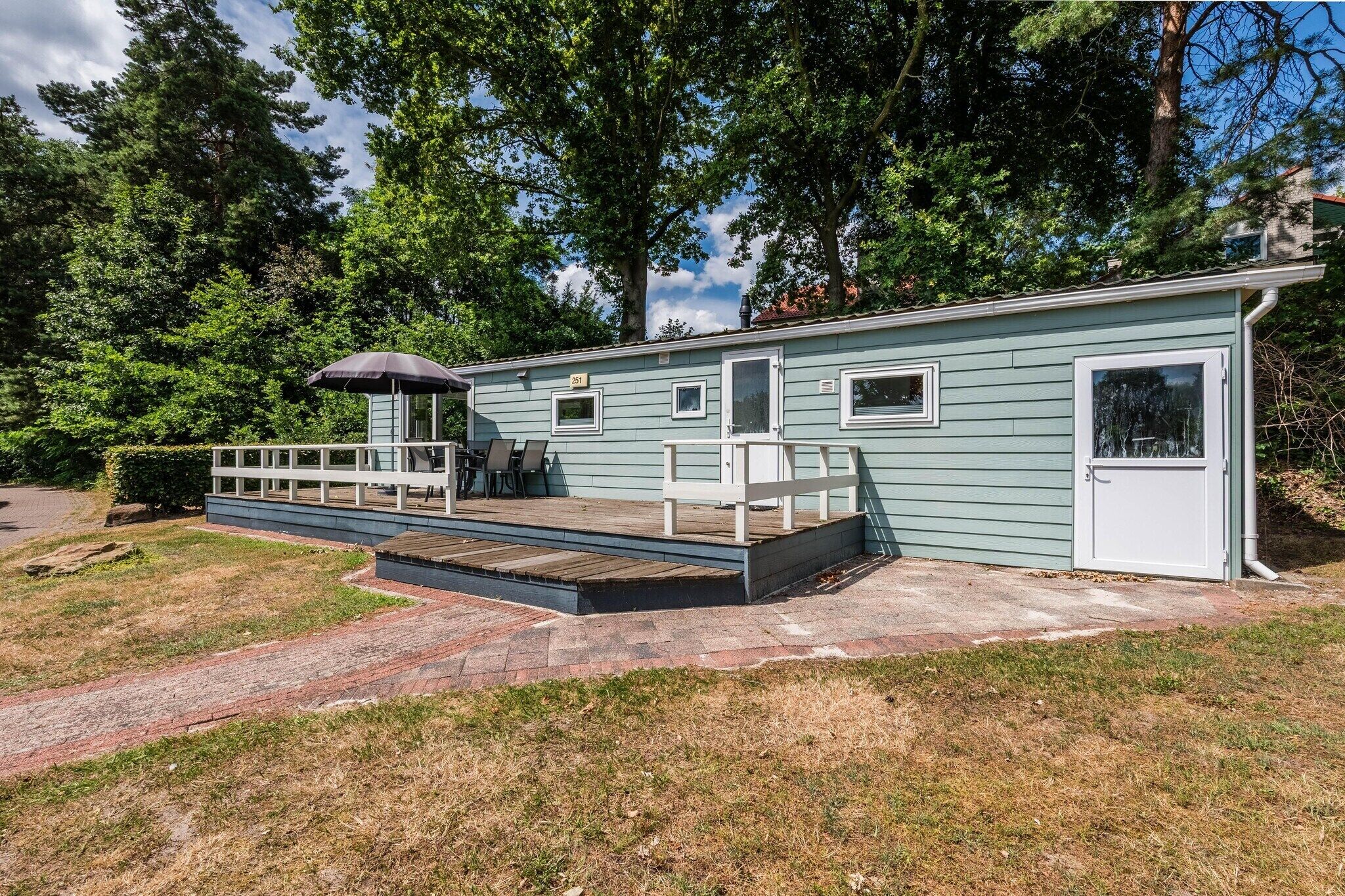 A single-story building with a covered patio area, a small deck, and a door with a window.
