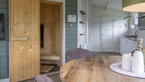 Une table de salle à manger en bois avec des chaises, une porte en bois et un coin cuisine avec des placards et une cuisinière.