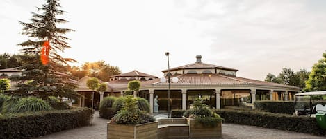 A building with a tiled roof, a statue in front, and a golf cart parked nearby.