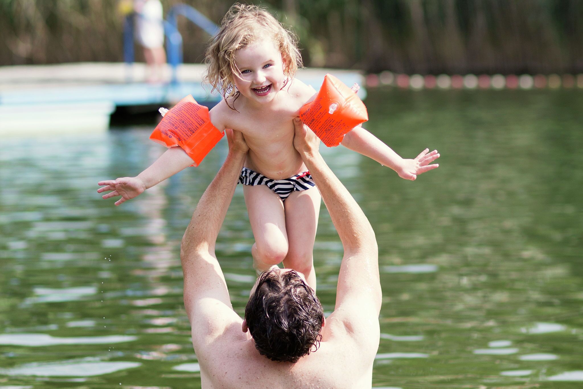A man holding a child above water.