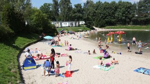 A beach with people sunbathing, swimming, and playing. - Modern Bungalow with Washer (Arcen)