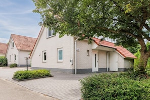 A two-story building with a red-tiled roof, white brick walls, and a small front garden.