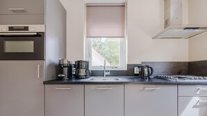 Uma cozinha moderna com forno embutido, cafeteira, chaleira e pia.