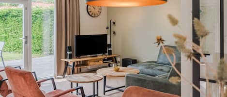 A modern living room with a television, two sofas, a coffee table, and a large window with curtains.