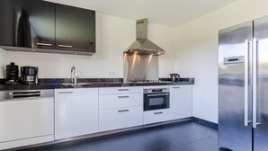 Una cocina moderna con electrodomésticos de acero inoxidable, horno empotrado y un refrigerador grande.