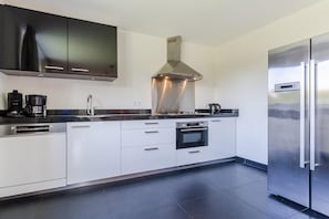 A modern kitchen with stainless steel appliances, a built-in oven, and a large refrigerator. - Group Getaway in Arcen (Arcen)